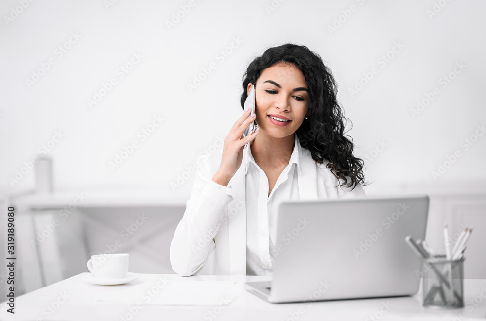 Smiling latin girl talking on the phone at coffee break Smiling latin girl talking on the phone at coffee break