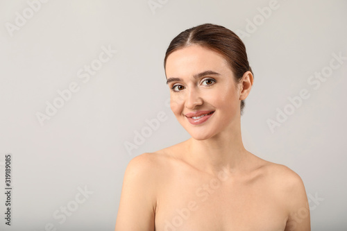 Beautiful young woman with healthy skin on light background