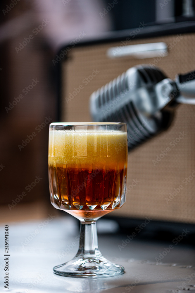 Blood and Sand cocktail, in the background a vintage retro microphone. Blood and Sand cocktail, in the background a vintage retro microphone.