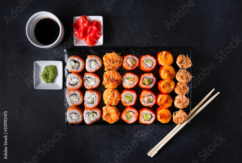 set of Japanese rolls with salmon caviar and cheese on a black background top view, pickled ginger, wasabi, soy sauce, sticks