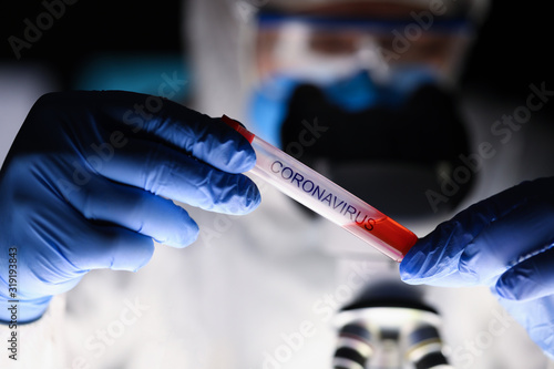 Male chemist hand in blue protective gloves hold test tube closeup background