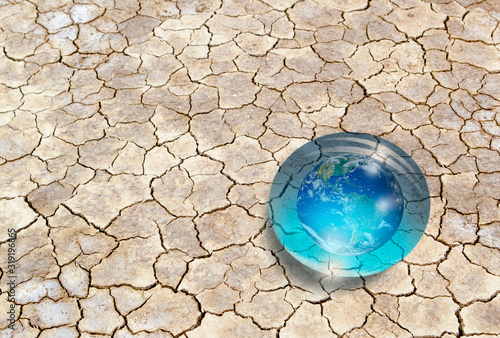 The glass globe (the world) in the form of drops on dry soil - Global warming and ecology concept "Elements of this image furnished by NASA "