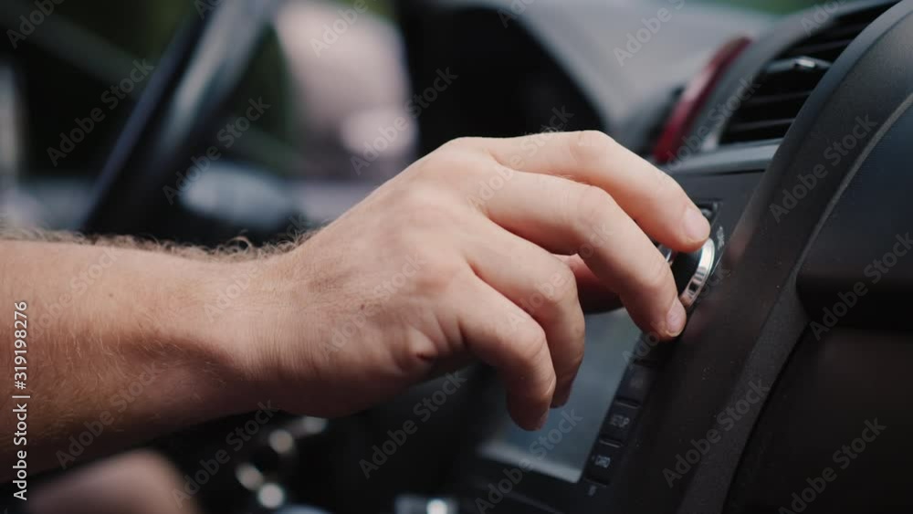 Male hand adjusts the tuning of the car radio Male hand adjusts the tuning of the car radio