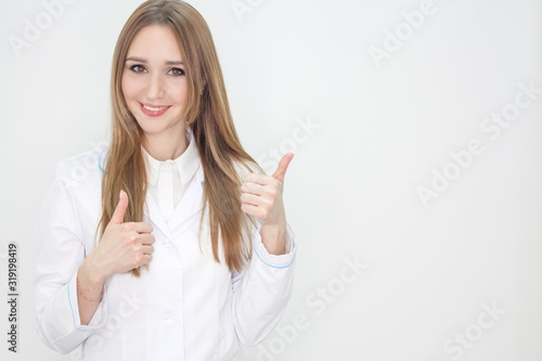 The doctor in a coat is isolated on a white background, the girl in a white coat smiles and looks into the frame. Clinic advertising concept.