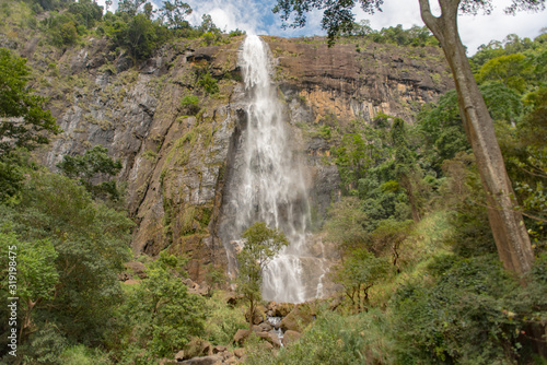 Sunny day in the Tropical waterfall falls from the mountain cliff to the jungle, serene landscape of Diyaluma falls.