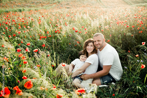 Charming family sits among the poppies