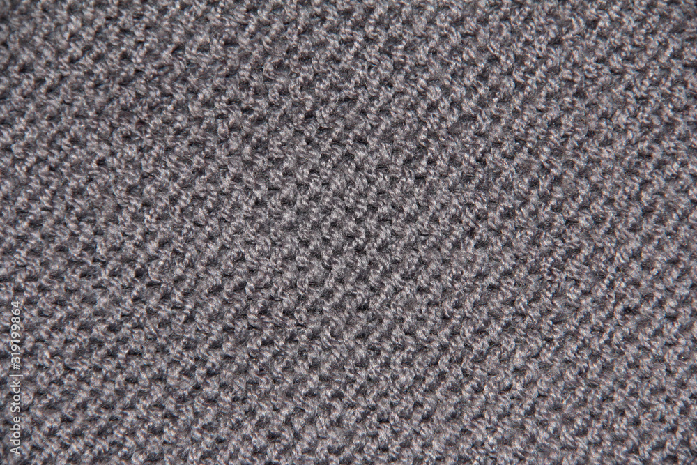 Grey textile background. Knitting with grey yarn. The texture of the knitted fabric. Grey textile background. Knitting with grey yarn. The texture of the knitted fabric.