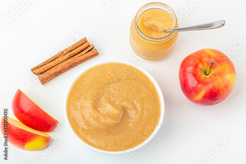 Fresh homemade applesauce in white bowl and jar with fruit puree on white table. The concept of proper nutrition and healthy eating. Organic and vegetarian food. Baby food. Copy space for text