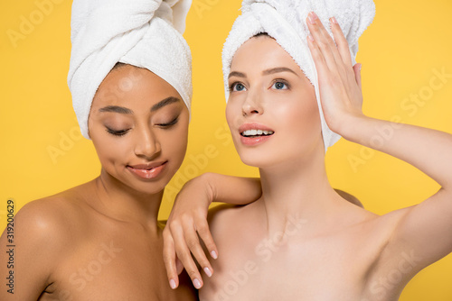 multiethnic young woman with towels on heads, isolated on yellow