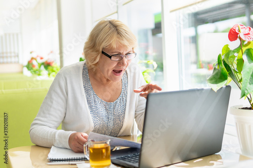 A woman with a laptop looks at a document in a cafe, office © Luca9257