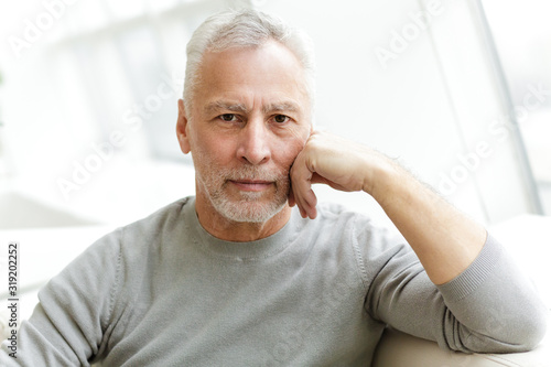 Photo of handsome mature man posing and looking at camera while sitting