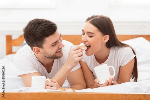 Loving Couple Feeding Each Other Having Morning Date In Bedroom