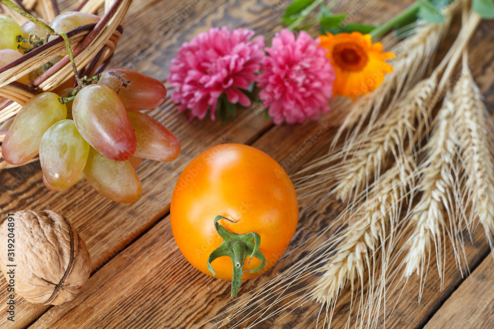 Tomato, walnuts and flower over the wooden natural background.