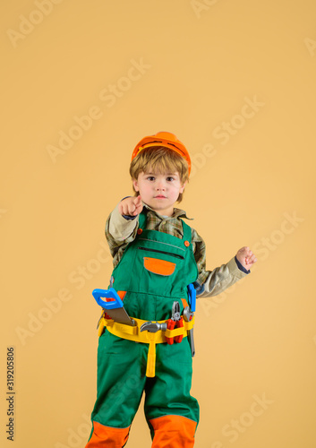 Work with tools. Repair. Little boy in builder uniform with tools belt. Little kid repairman pointing finger to you. Builder boy in helmet and toolbelt. Happy boy with tools for building. Child game.