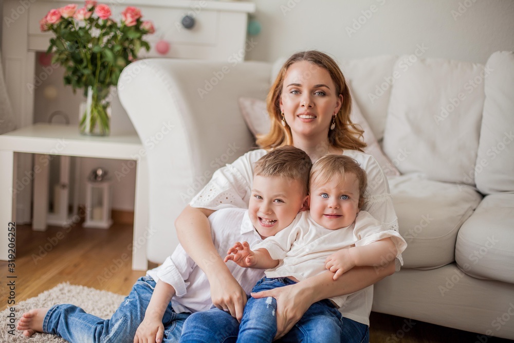 Beautiful young mother, little son, little daughter are sitting on the sofa at home. Mothers Day. A happy family. Cozy. Beautiful young mother, little son, little daughter are sitting on the sofa at home. Mothers Day. A happy family. Cozy.