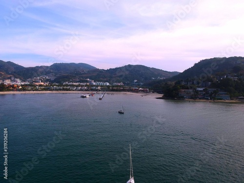 Panoramic View of Patong Beach buildings boats parasailing jetski people on the beach and beautiful blue skies long tail boats photo