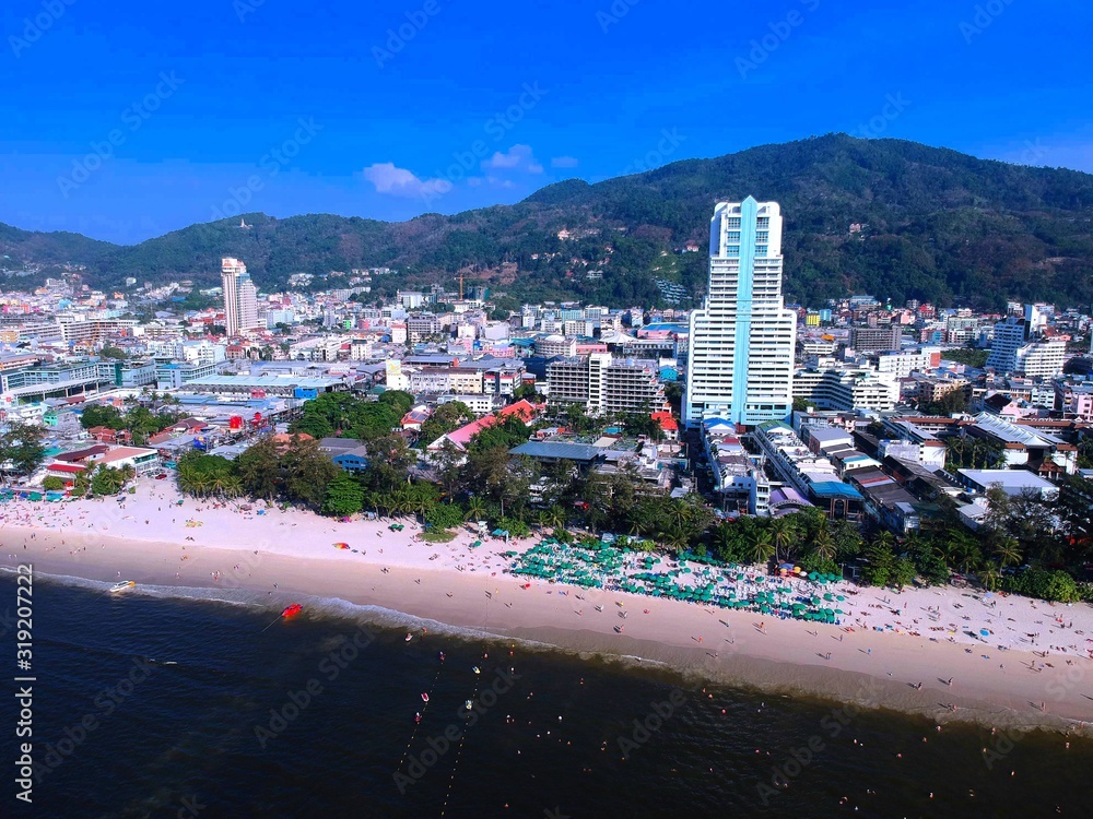 Panoramic View of Patong Beach buildings boats parasailing jetski people on the beach and beautiful blue skies long tail boats