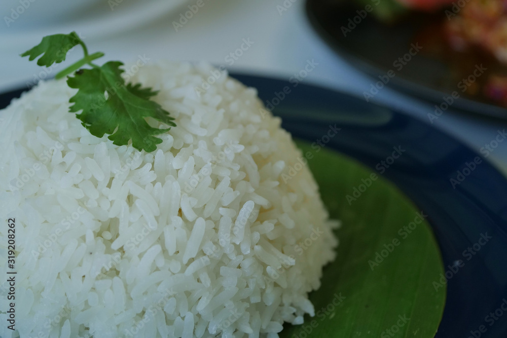 Thai food, white cooked rice above banana leaf on dish Thai food, white cooked rice above banana leaf on dish
