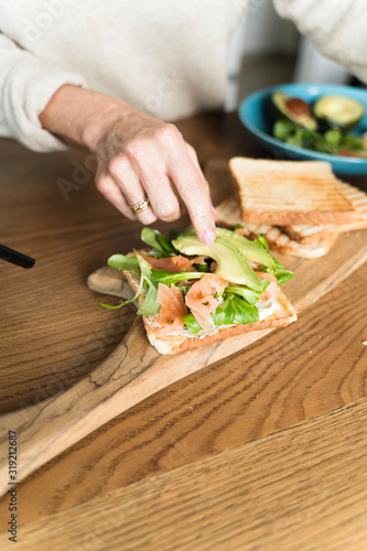 Adult woman preparing an healthy avocado sandwich on a cutting board