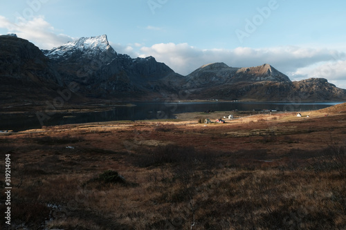 View into a valley in Lofoten Islands. Mountain peaks covered by snow, bushes and grass in autumn's colors. 