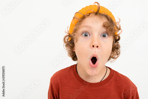 Portrait of charming boy with curly hair, yellow hat is scared isolated on white background
