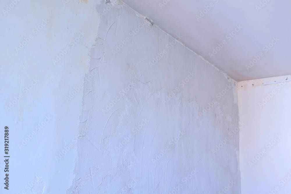 Putty wall aligning with plaster in room, renovation construction works and overhaul. Finishing repairing works. Texture of gray cement wet plaster and dry white wall. Plastering coating wall surface.