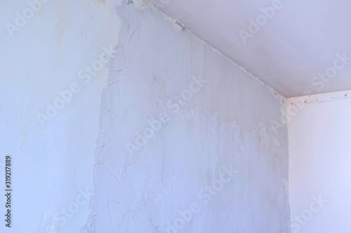 Putty wall aligning with plaster in room  renovation construction works and overhaul. Finishing repairing works. Texture of gray cement wet plaster and dry white wall. Plastering coating wall surface.