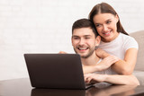 Guy Working On Laptop Sitting With Girlfriend On Couch Indoor