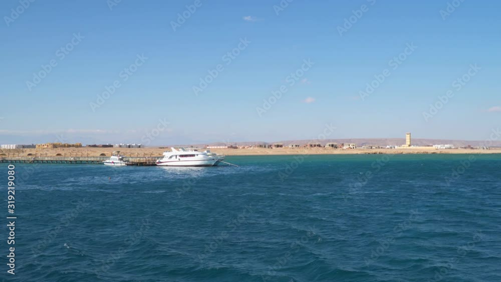 White yacht and motor boat at the pier. Shore of the Red Sea in Egypt. View from the sea White yacht and motor boat at the pier. Shore of the Red Sea in Egypt. View from the sea