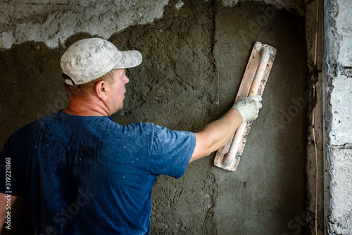 Worker applying plaster on the wall using a trowel.