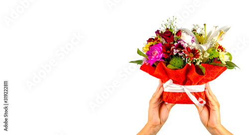 Women's hands holding colorful bouquet of flowers. Composition of various flowers in wrapping basket on isolated white background.