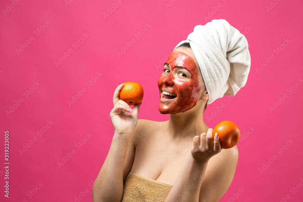 Beauty portrait of woman in white towel on head with red nourishing mask on face. Skincare cleansing eco organic cosmetic spa relax concept. A girl stands with her back holding an orange mandarin. Beauty portrait of woman in white towel on head with red nourishing mask on face. Skincare cleansing eco organic cosmetic spa relax concept. A girl stands with her back holding an orange mandarin.