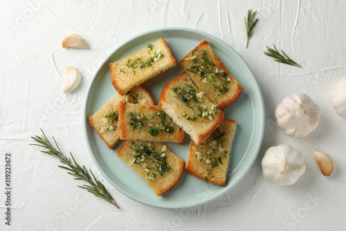 Plate with toasted garlic bread on white background, top view