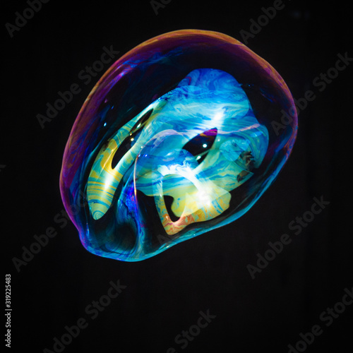 Colorful creative amorphous soap bubble floating with a black background © Colozio