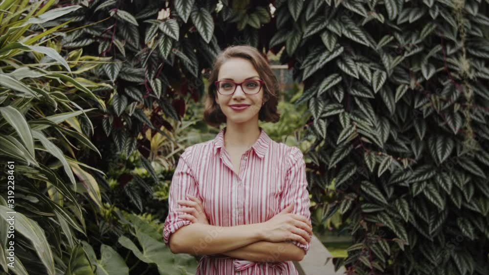 Young woman standing in botanical garden, looking at camera. Young woman standing in botanical garden, looking at camera.