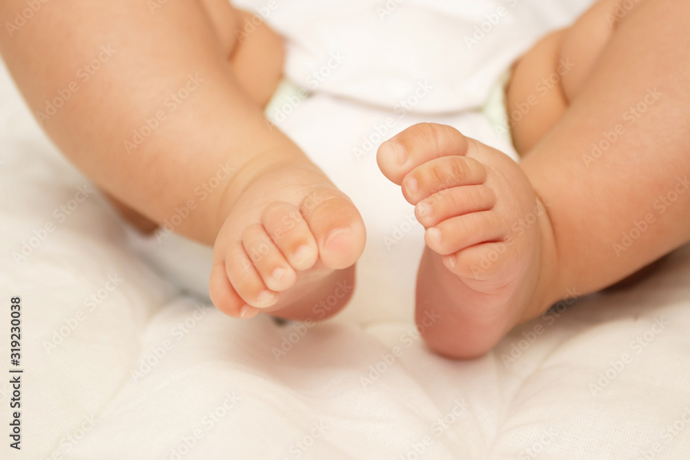 Legs of infant on the white blanket, bedroom, blurred background Legs of infant on the white blanket, bedroom, blurred background