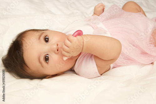 Little cute baby girl on the blanket with a heart shaped toy