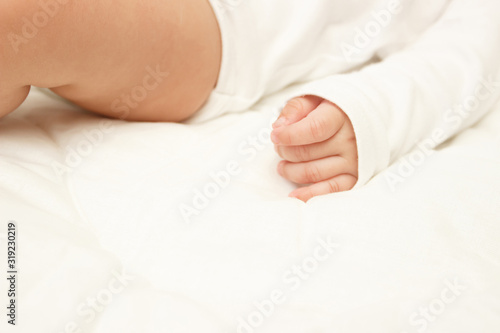 Body of infant on the white blanket, bedroom, blurred background