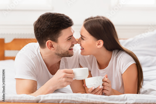 Couple Having Morning Coffee Lying In Bed At Home