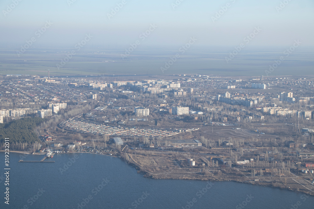 Aerial view of the city. Foggy day, sunny weather and blue sky. 400 meters above the ground. Small houses and river view. Winter  sky.