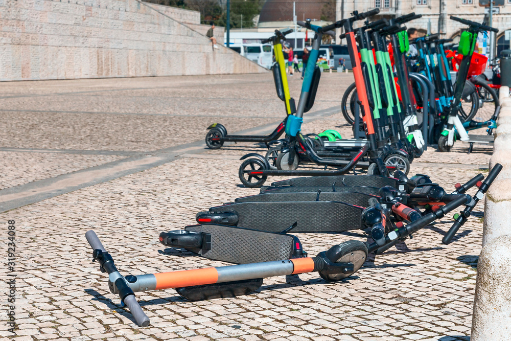 many modern electric scooters for rent in a city parking lot in the Portuguese capital on a sunny spring day