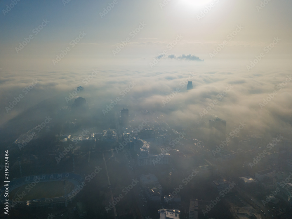 Naklejka premium Aerial drone view. A foggy morning in Kiev, the silhouettes of houses are visible through the autumn fog.