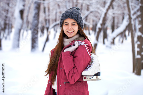 Happy beautiful brunette woman with ice skates go to the rink, winter outdoors