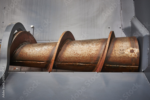 Road construction machinery. Asphalt feed auger in paver hopper