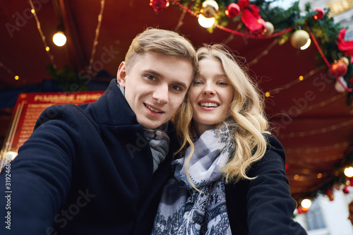 elegant romantic couple in love making selfie, looking to the camera and posing on festive decorations background.