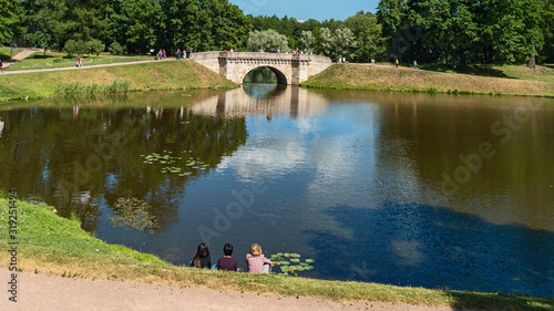 Konstfotografi young girls have a rest on the shore of a picturesque pond in the suburbs of St