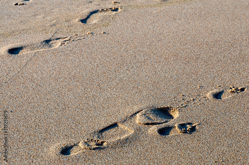 large and small footprints of human feet on the wet sea sand of the beach of the Portuguese city of Sintra