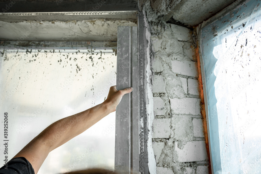 The plasterer repairs the corners of the window with a spatula and plaster. Construction finishing works. The plasterer repairs the corners of the window with a spatula and plaster. Construction finishing works.