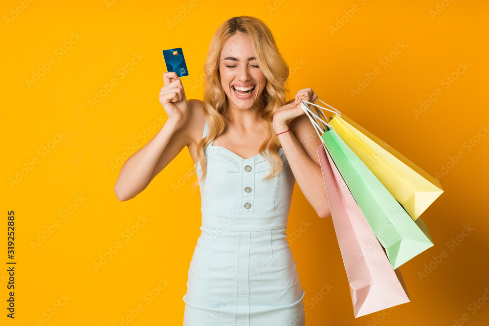 Shopping concept. Overjoyed woman holding credit card and paper bags Shopping concept. Overjoyed woman holding credit card and paper bags