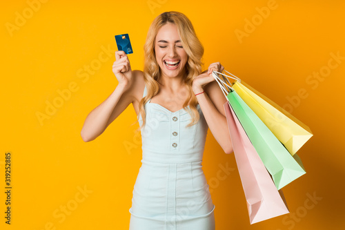 Shopping concept. Overjoyed woman holding credit card and paper bags